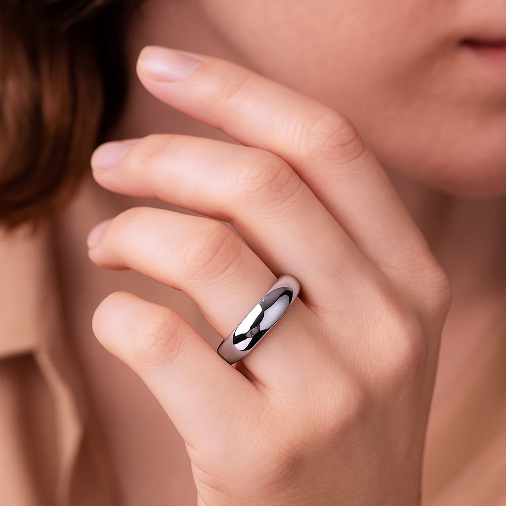 Side view of a woman's hand elegantly with a domed platinum wedding ring with a glossy finish.