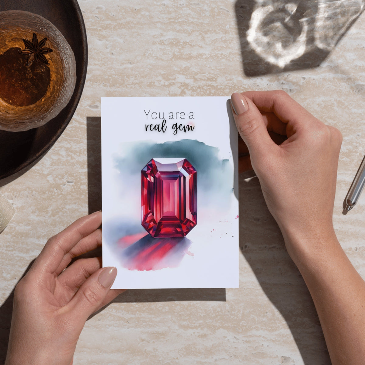 hands holding a You are a real Gem Watercolor Emerald Shape Ruby Birthstone Greeting Thank you Card