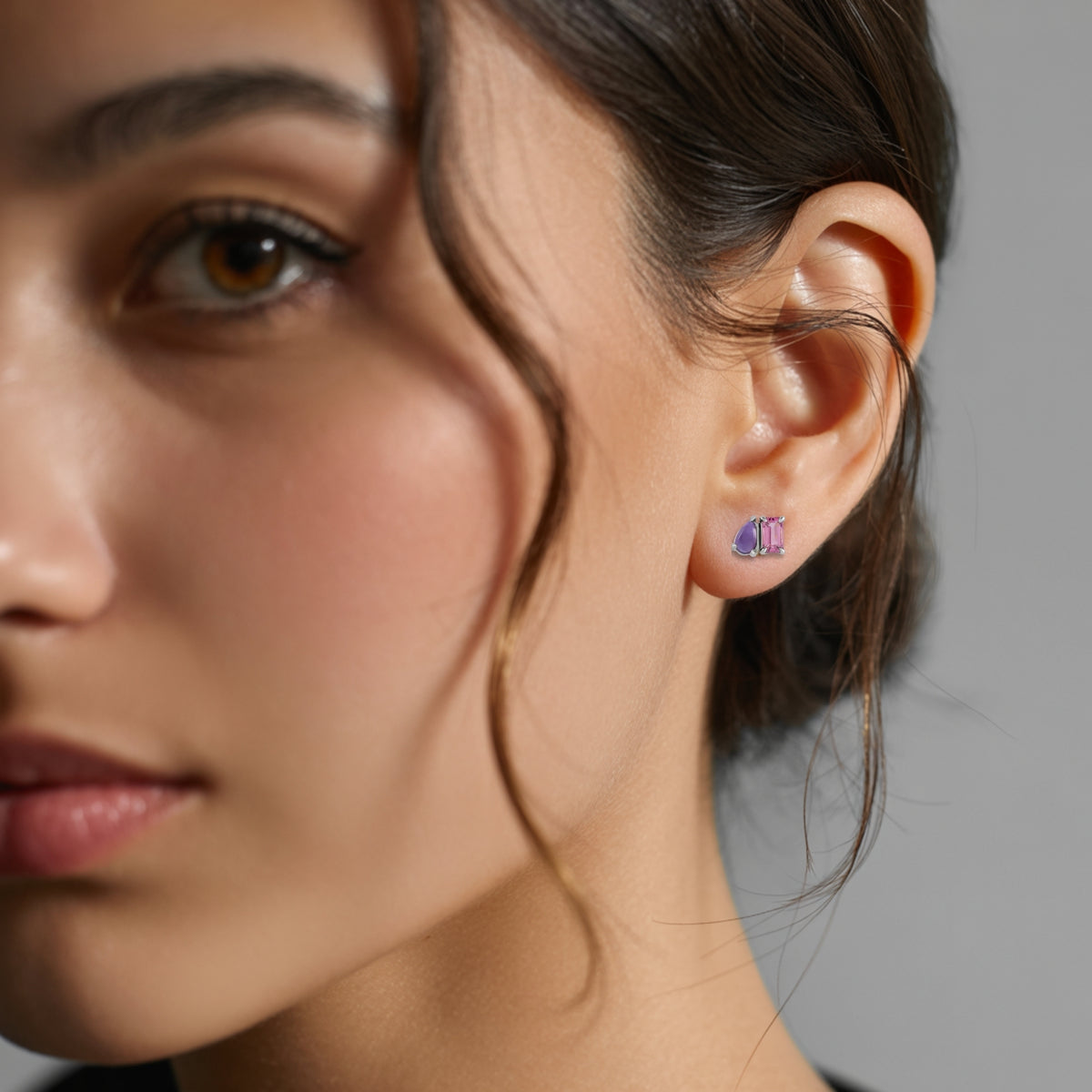Emerald cut Pink Tourmaline & Pear Amethyst Two-Stone Birthstone Stud Earrings in rose gold on a womans ear