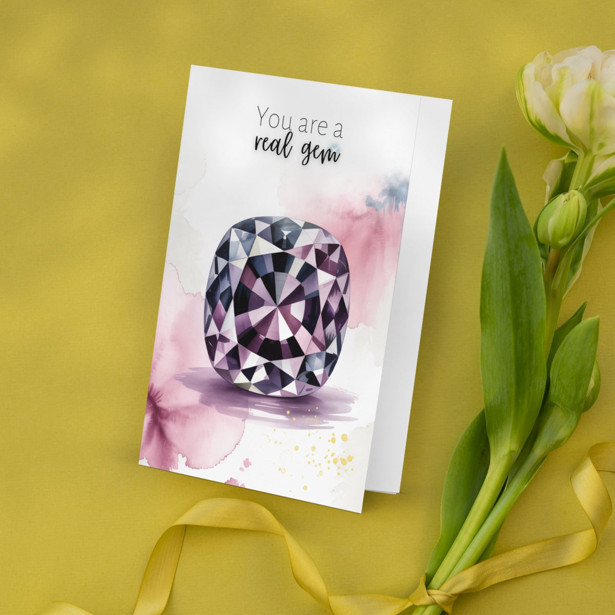 Greeting card with a watercolor spinel illustration and text 'You are a real gem' on a yellow background with flowers.