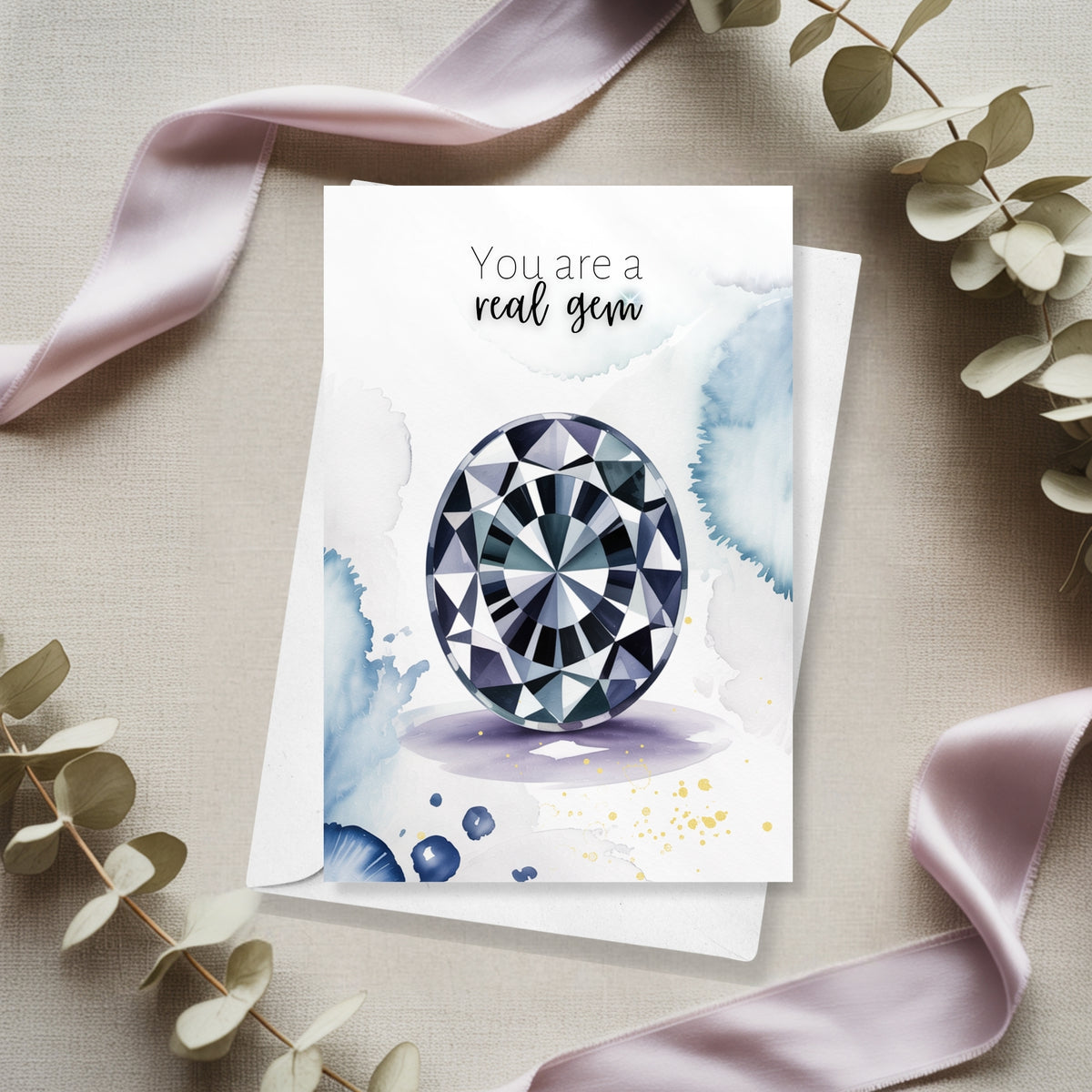 Greeting card with a gemstone illustration and 'You are a real gem' text, surrounded by ribbons and leaves on a neutral background.