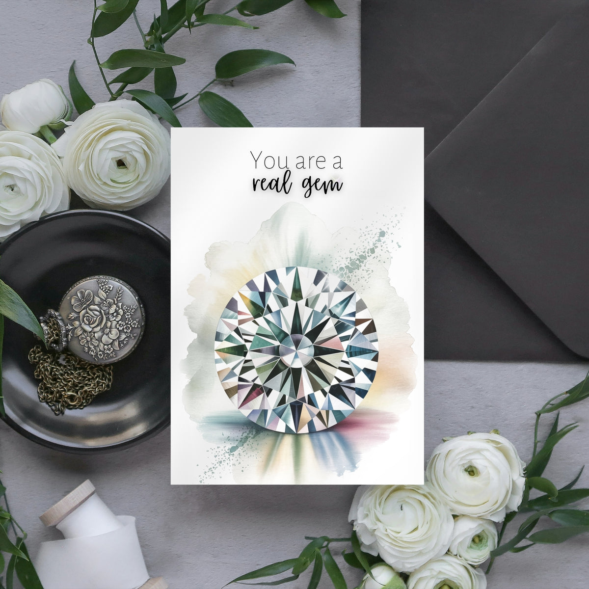 Greeting card with diamond illustration and floral arrangement on a gray surface
