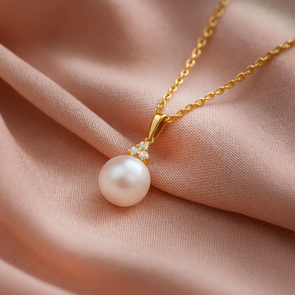 White Akoya Pearl Diamond Accented 14k Yellow Gold Dangle Pendant Necklace draped over pink fabric