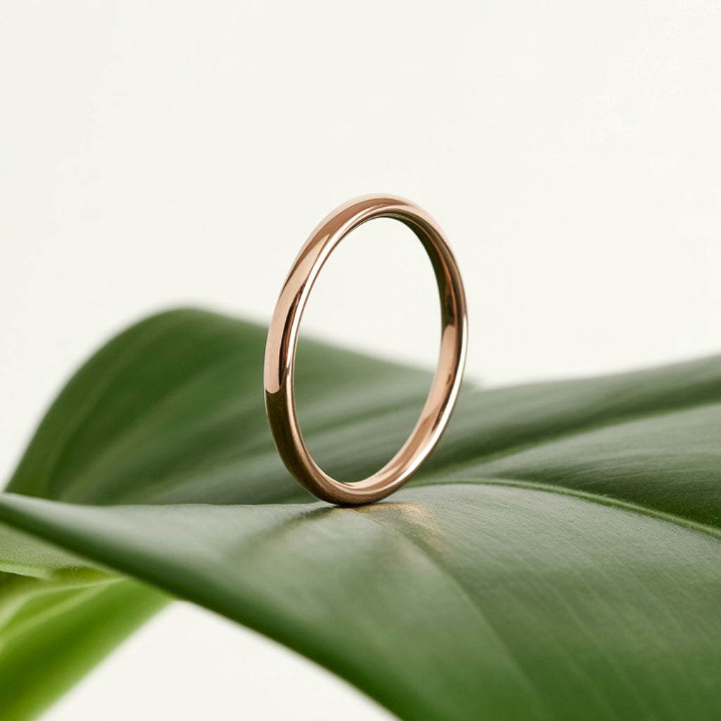 delicate 2mm wide domed rose gold band standing on a leaf