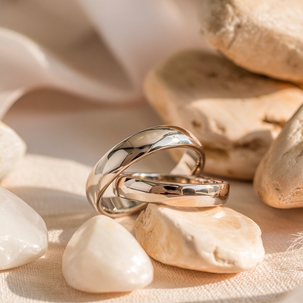 2 gold domed simple wedding bands laying on some rocks