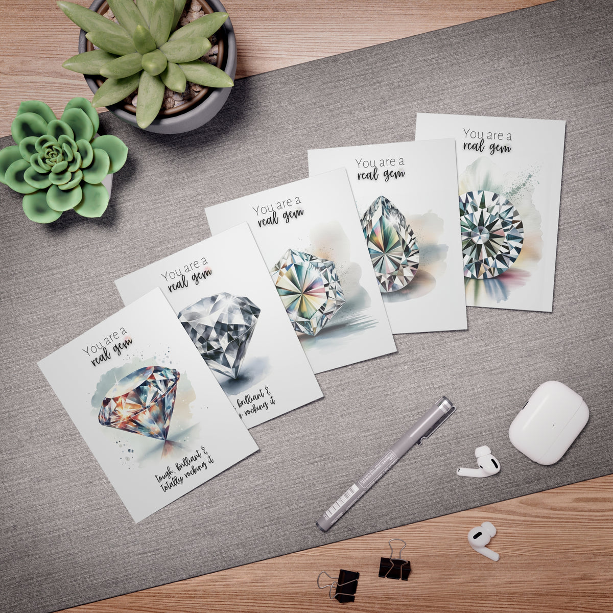 Set of folded cards with diamond watercolor illustrations and text laying on a table