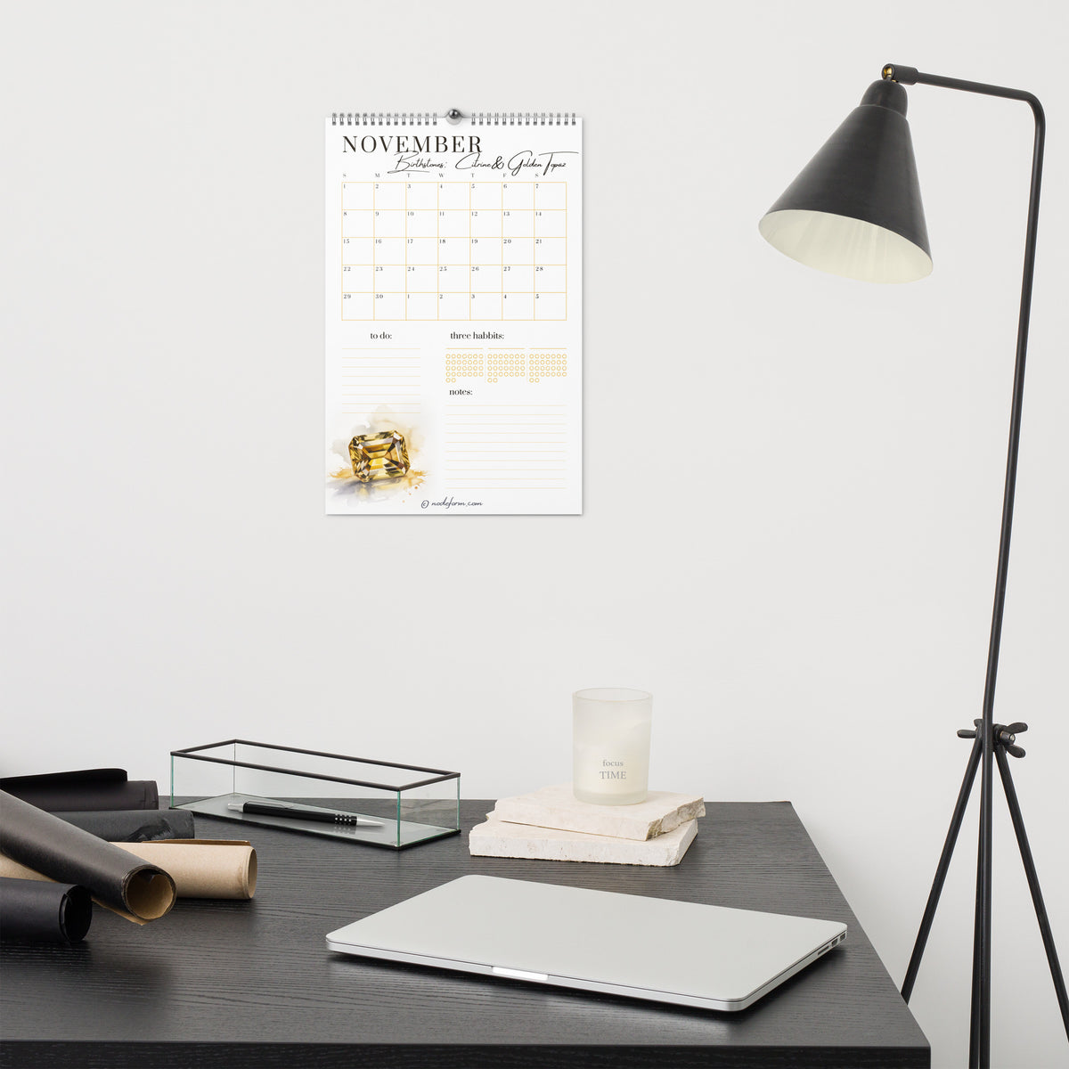 Wall calendar for November on a wall above a desk with office supplies.