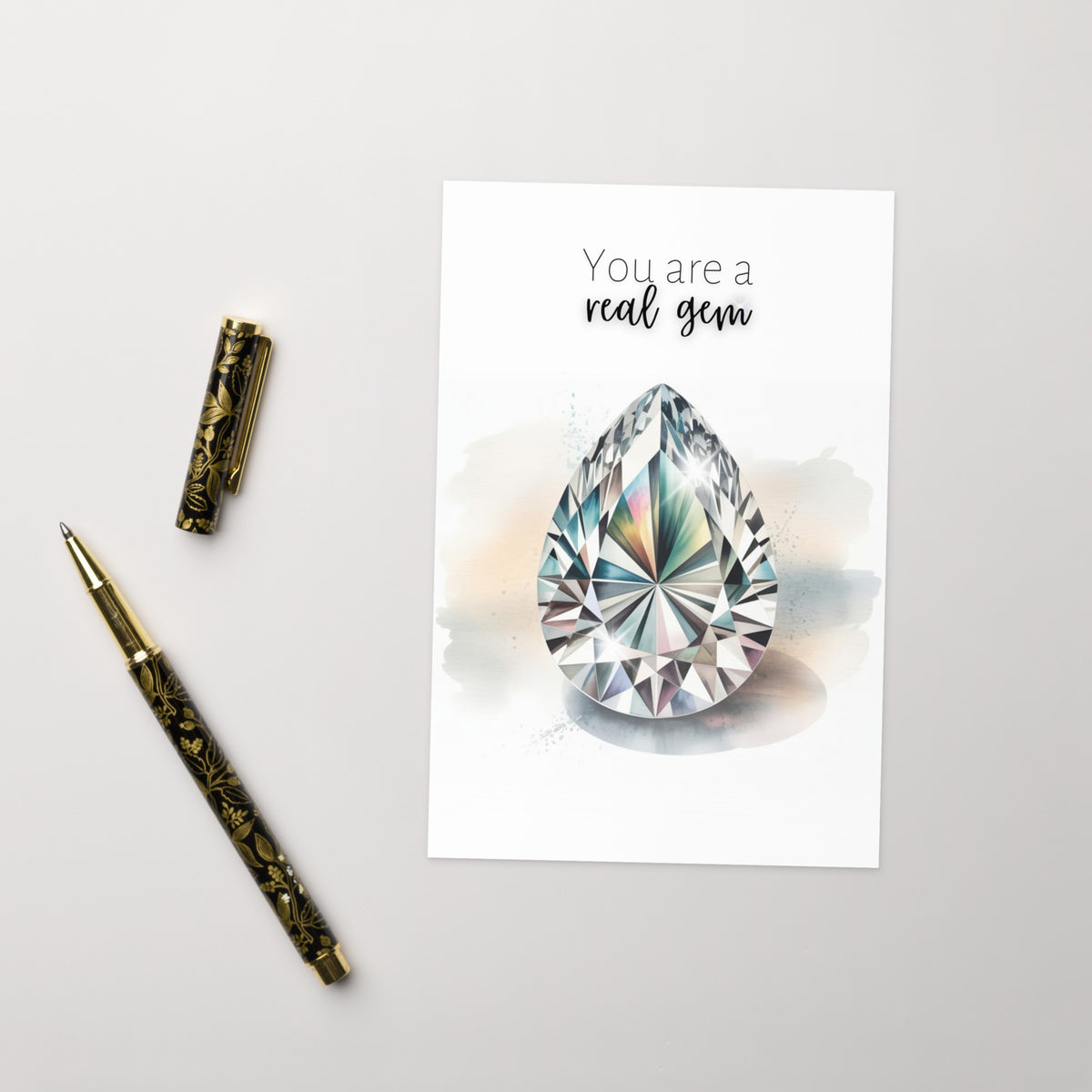 Card with teardrop-shaped gem and pen on a light gray background