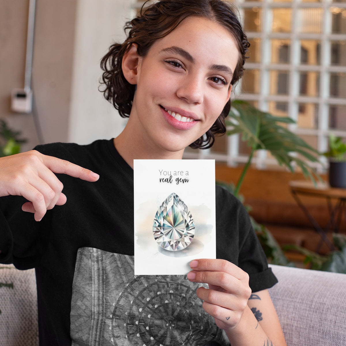 Person holding a card with a diamond illustration and text, sitting on a couch.