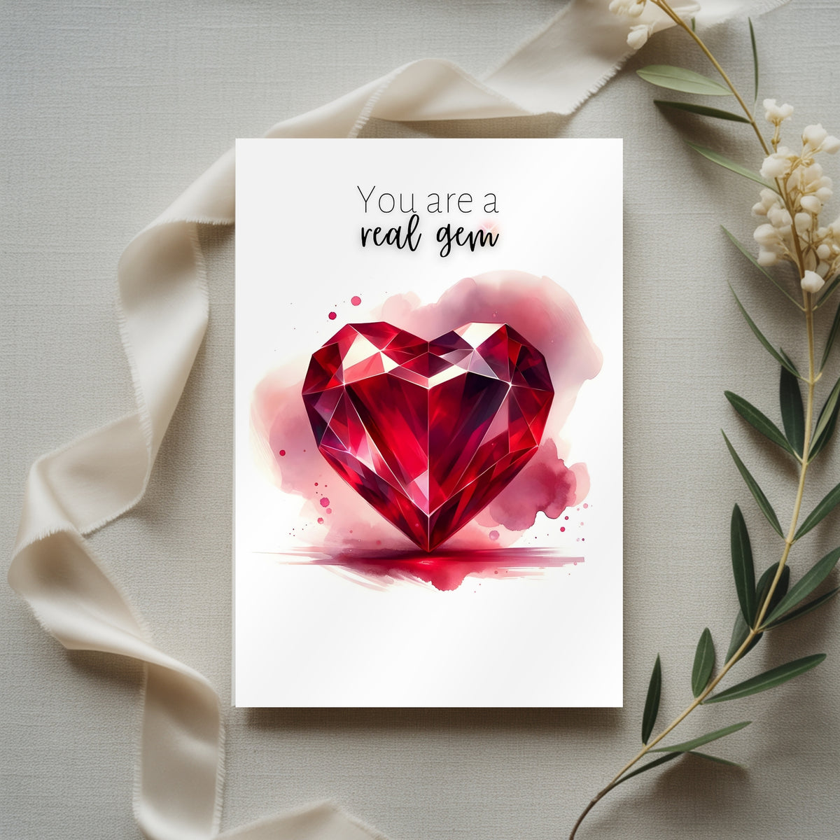 Card with a red ruby watercolor illustration and 'You are a real gem' text, surrounded by ribbons and flowers.
