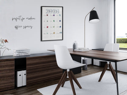 Modern office desk with a chair, lamp, and 2026 birthstone calendar on a white wall.
