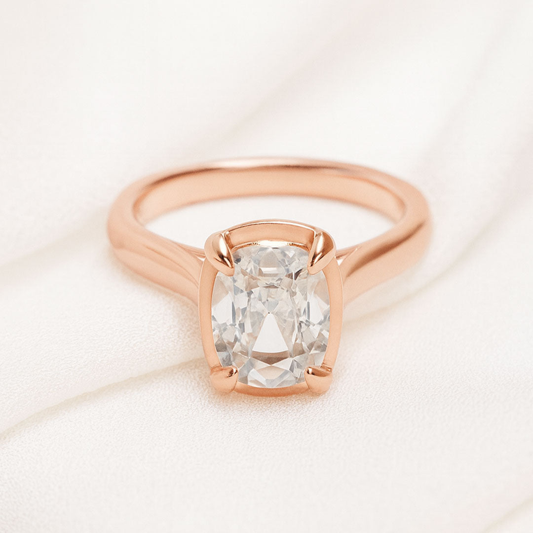 Taylor engagement ring  in rose gold with a large elongated antique cut cushion moissanite on a white fabric