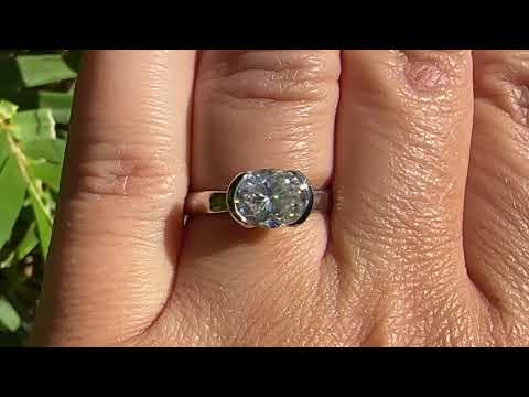 Video of white gold solitaire ring with large 1.9ct oval moissanite  in a half bezel setting on a persons hand