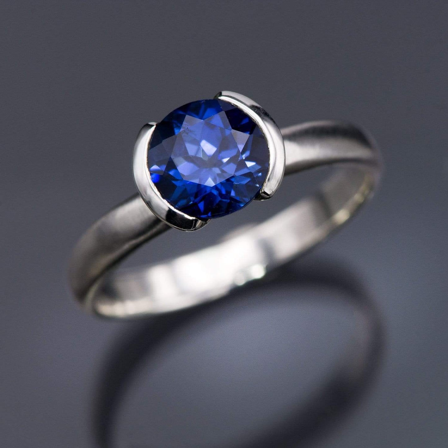 Lab Created Round Blue Sapphire Half Bezel Solitaire Engagement Ring Ring by Nodeform